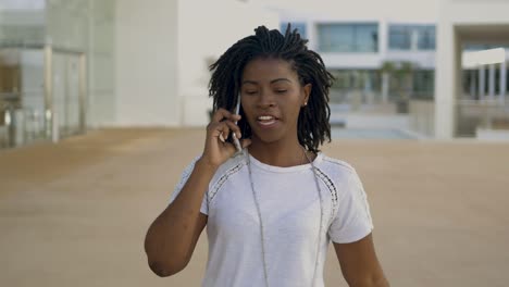 Front-view-of-happy-woman-with-dreadlocks-talking-on-phone.